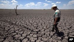FILE - A Texas State Park police officer walks across a cracked lake bed in San Angelo, Texas, Aug. 3, 2011.
