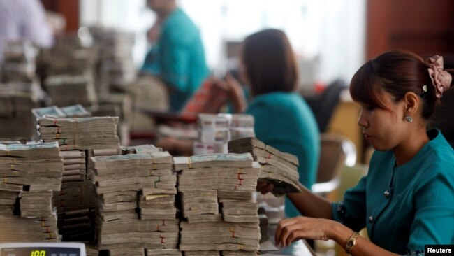 FILE - Workers count Myanmar's kyat banknotes at the office of a local bank in Yangon, April 2, 2012.