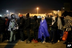 Migrants wait to register outside a processing center in the makeshift migrant camp known as "the jungle" near Calais, northern France, Oct. 26, 2016.