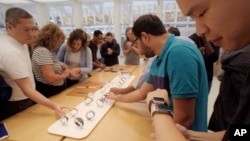 In this Sept. 21, 2018 file photo customers look at Apple Watches at an Apple store in New York. (AP Photo/Patrick Sison, File)
