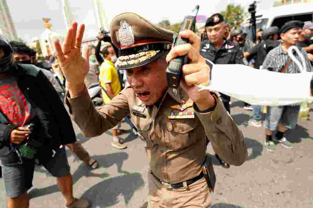 A police officer reacts during clashes between pro-democracy demonstrators and royalists during a anti-government protest on the 47th anniversary of the 1973 student uprising, in Bangkok, Thailand.
