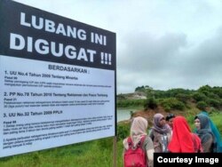 Aktivis lingkungan memasang plang sebagai bentuk protes atas lubang tambang yang belum direklamasi. (Sumber: Jatam Kaltim)