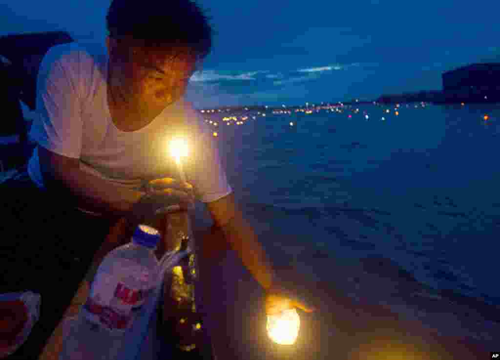 A man releases paper lanterns to float in Shwe Kyin creek during the annual light festival in Bago, about 183 kilometers from Yangon, Myanmar.&nbsp; The ritual is believed to bring good fortune at the end of Buddhist Lent.