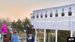 Residents look at a presidential election poster depicting the candidates in Ashgabat, Turkmenistan, February 7, 2012.