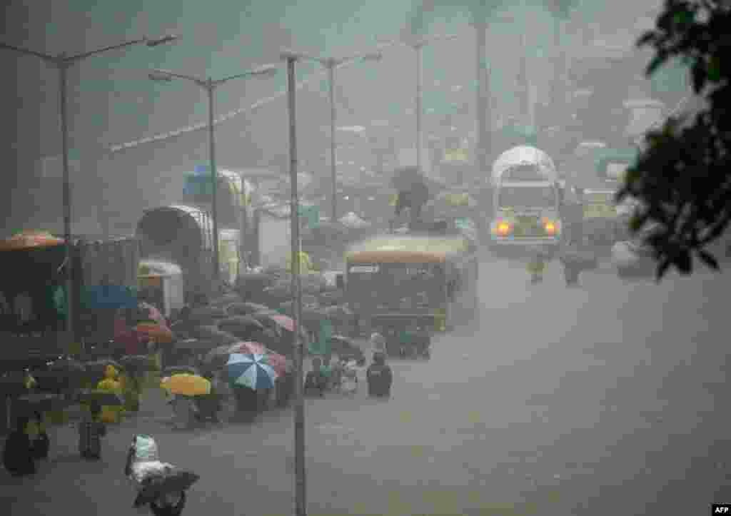 People wade along a flooded street during heavy rain showers in Mumbai, India.