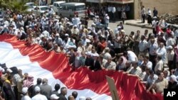 Syrian supporters of President Bashar Assad carry a giant national flag during a protest in al-Qarya village, in the southwestern Suwayda province, Syria, July 1, 2011