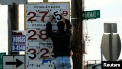 A man changes the price for a gallon of gasoline at a gas station in Medford, Massachusetts.