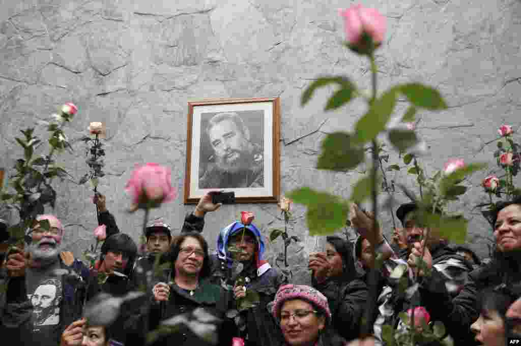 People hold flowers in front of a portrait of Cuban historic revolutionary leader Fidel Castro at the Cuban embassy in Bogota, Colombia, Nov. 26, 2016. Fidel Castro died late Friday in Havana, his brother, President Raul Castro, announced on national television. Castro&#39;s ashes will be buried in the historic southeastern city of Santiago on Dec. 4 after a four-day procession through the country.