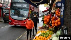 资料照片：人们戴着口罩走在伦敦一处购物街。(2021年12月24日)