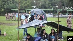 Refugees take cover from the rain under an improvised shelter at a military zone for people displaced by earthquakes in Cuilapa, Guatemala, September 19, 2011.