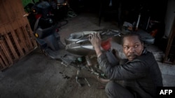A Haitian mechanic works on a motorcycle at a workshop in the commune of Quilicura in Santiago, on April 26, 2018.