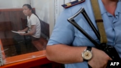 一名因进入哈萨克斯坦寻亲而被控非法入境的41岁哈萨克族中国公民坐在被告囚笼中在扎尔肯特市的一家法庭参加听证。(2018年7月13日)