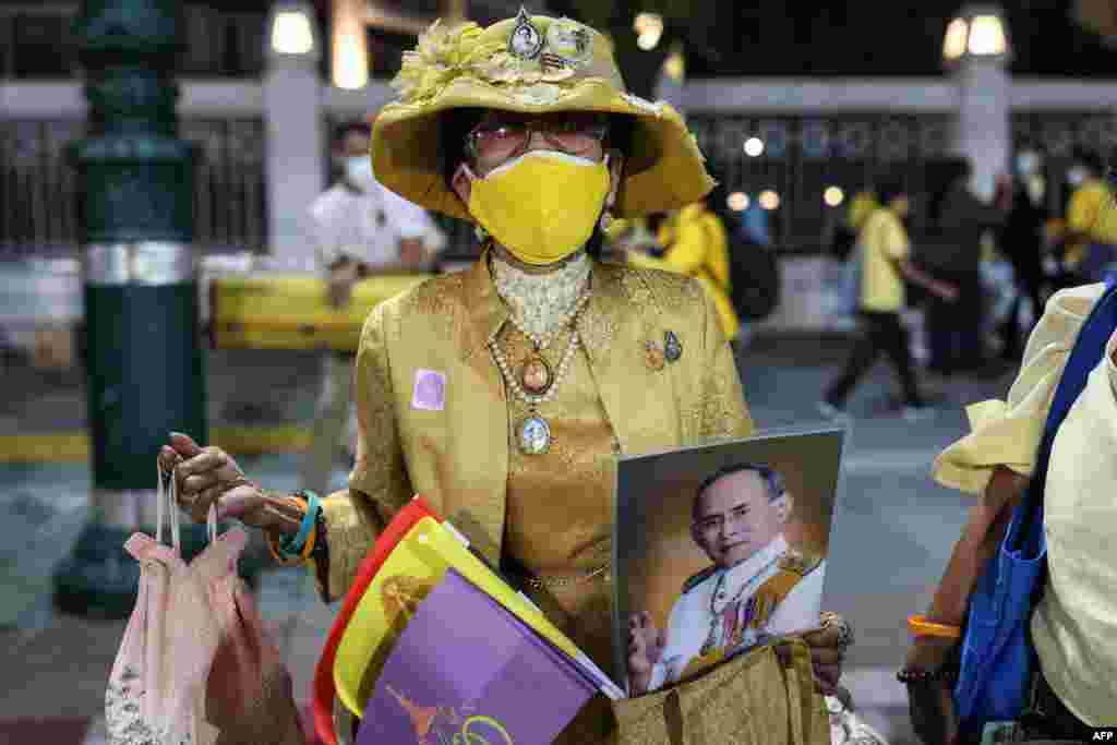 A royalist supporter holds a portrait of the late king Bhumibol Adulyadej while waiting for the motorcade of Thailand&#39;s King Maha Vajiralongkorn to pass in Bangkok.