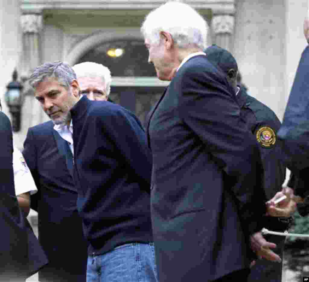 Actor George Clooney, center, Rep. Jim Moran, D-Va, back, and Clooney's father, Nick Clooney, right, are arrested during a protest at the Sudanese Embassy in Washington, Friday, March 16, 2012. The demonstrators are protesting the escalating humanitarian