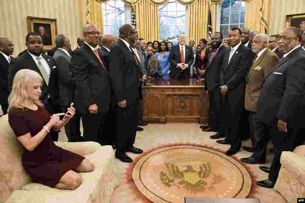 Kellyanne Conway, White House counselor, checks her phone after taking a photo of U.S. President Donald Trump and leaders of historically black universities and colleges in the Oval Office of the White House in Washington, D.C., Feb. 27, 2017.