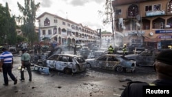 Burnt-out cars are seen at the scene of a blast in Abuja, June 25, 2014. At least 21 people were killed when a suspected bomb tore through a crowded shopping district in the Nigerian capital Abuja during rush hour on Wednesday, police said, adding to the 