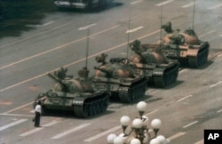 FILE - A Chinese man stands alone to block a line of tanks heading east on Beijing's Cangan Boulevard in Tiananmen Square, June 5, 1989.