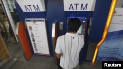 A man uses an automated teller machine (ATM) machine at a shopping center in Yangon, Burma, May 27, 2012.