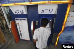 FILE - A man uses an automated teller machine (ATM) machine at a shopping center in Yangon, Burma, May 27, 2012.