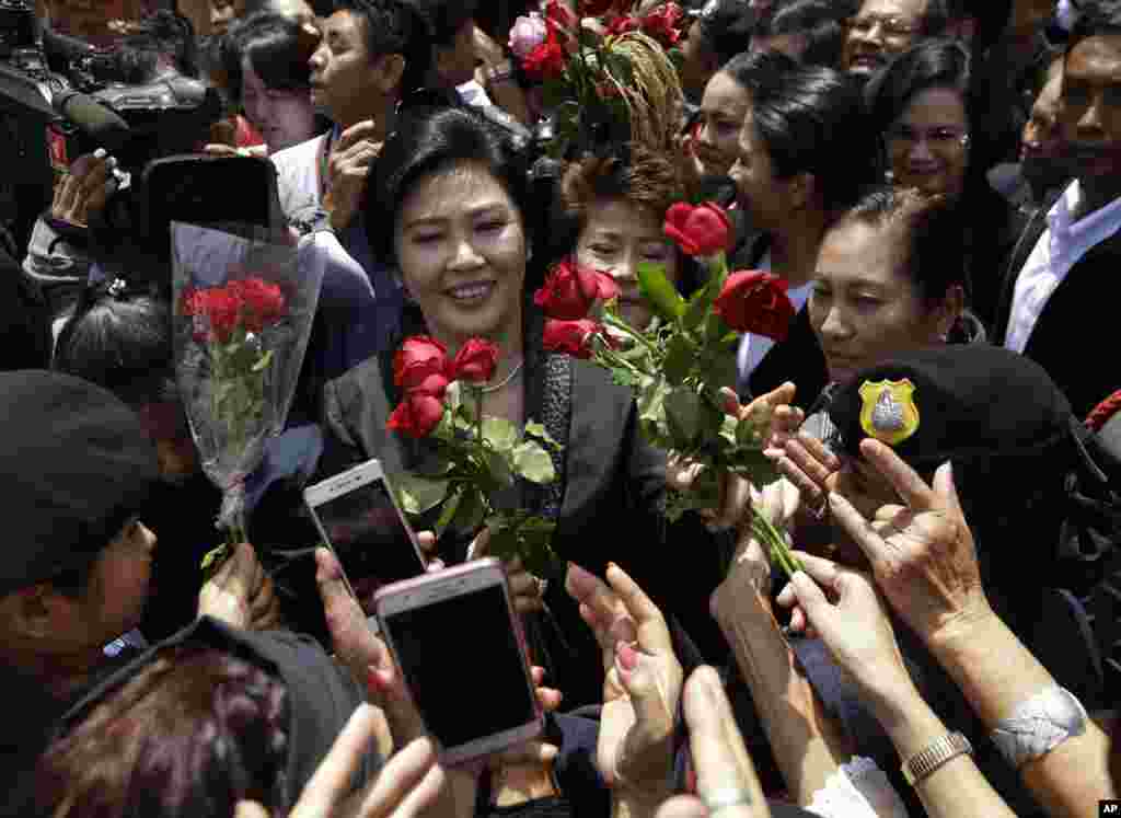 Mantan PM Thailand Yingluck Shinawatra (tengah) menerima bunga dari para pendukungnya setelah mengaku tidak bersalah atas tuduhan penyalahgunaan subsidi berasa ketika menjabat, di pengadilan Bangkok, Thailand.