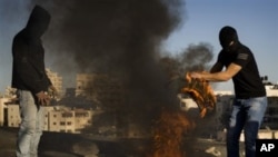 Masked Palestinian youths burn tires during clashes with Israeli police officers, not seen, in the east Jerusalem neighborhood of Issawiyeh, 30 Nov 2010