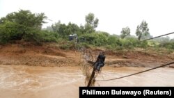 Um homem atravessa o rio Umvumvu depois do ciclone Idai que atingiu Moçambique ter chegado ao Zimbabwe