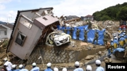 Des secouristes recherchent des personnes portées disparues dans une maison endommagée par de fortes pluies dans la ville de Kumano, dans la préfecture d'Hiroshima, au Japon, le 9 juillet 2018. Kyodo / via REUTERS 