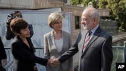 Iraqi Foreign Minister Ibrahim al-Jaafari, right, shakes hands with the Australian Ambassador to Iraq Lyndall Sachs, as Australian Foreign Minister Julie Bishop looks on in Baghdad, Iraq, Saturday, Oct. 18, 2014.