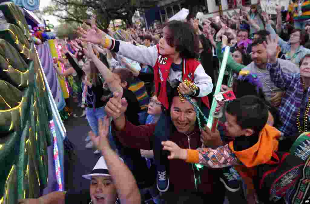 Участники карнавала в разукрашенных масках едут на особых платформах, и разбрасывают яркие пластмассовые бусы