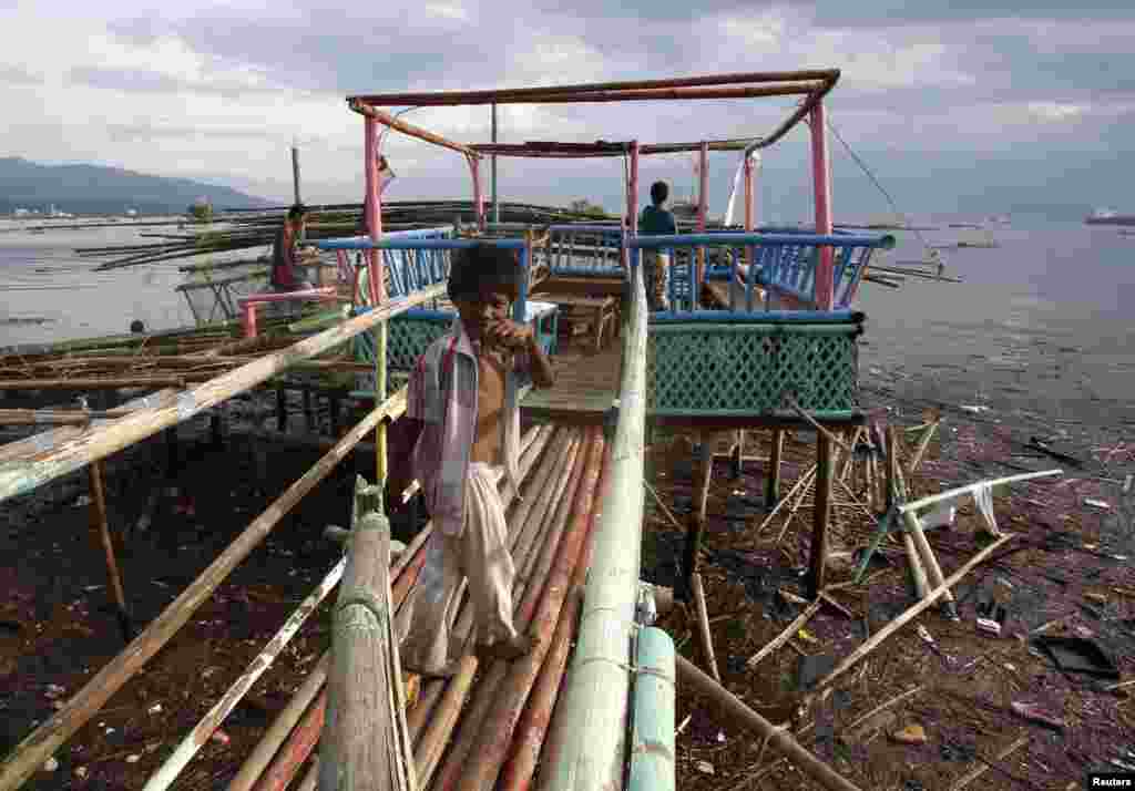 A young boy turns to look at the camera as residents repair a roofless stilt house damaged by Typhoon Rammasun in Batangas city, south of Manila, July 17, 2014.