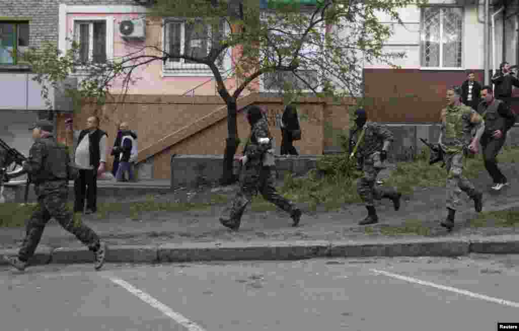 Pro-Russian armed men run near the local police headquarters in Luhansk, eastern Ukraine.