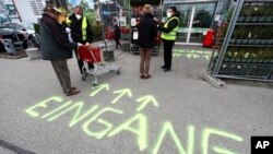 Security employee disinfect shopping carts at the entrance of a garden store in Munich, Germany, Monday, April 20, 2020.
