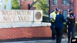 An officer (R) checks an ID outside of the Washington Navy Yard in the U.S. capital on September 17, 2013.