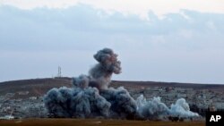 FILE - Smoke rises above the Syrian city of Kobani after an airstrike by the U.S.-led coalition, seen from a hilltop on the outskirts of Suruc, near the Turkish border. 