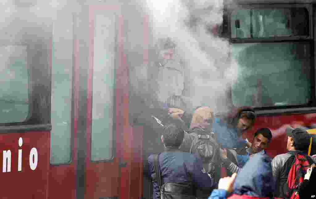 Commuters rush out of a bus after it was filled with smoke from a smoke grenade launched by police at nearby protesters who are demanding improvements to the public transportation, in Bogota, Colombia.