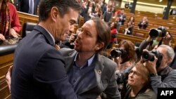 El presidente español Pedro Sánchez es felicitado por su vicepresidente Pablo Iglesias, del izquierdista Unidas Podemos, con quien formó coalición de gobierno en noviembre.