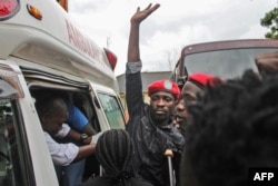 Ugandan singer-turned-politician Robert Kyagulanyi, center, better known as Bobi Wine, reacts as he gets into an ambulance after being released on bail at the High Court in Gulu, northern Uganda, Aug. 27, 2018.