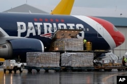Palettes of N95 respirator masks are off-loaded from the New England Patriots football team's customized Boeing 767 jet on the tarmac, Thursday, April 2, 2020, at Logan Airport in Boston, after returning from China.