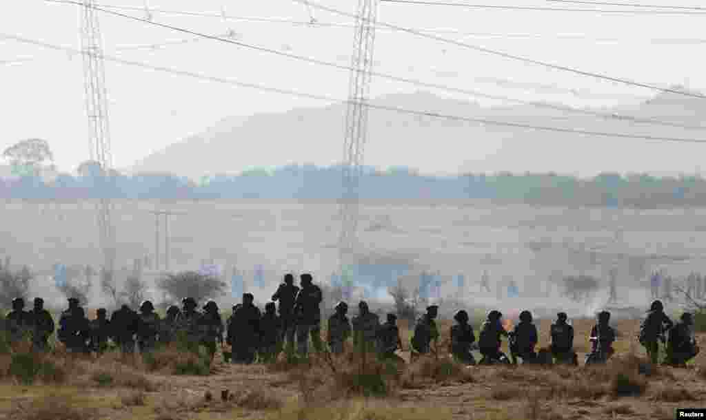 Policemen fire at striking miners outside the mine in Rustenburg, August 16, 2012. 