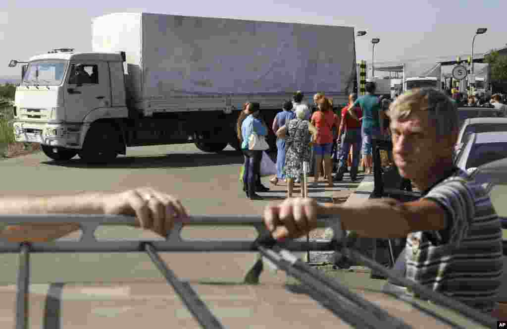 در حالی که کامیون های کمک روسیه پس از تحویل بار به کشور بازمی گردد، عده ای از آوارگان اوکراینی در مرز منتظر بازگشت به مناطق شرقی اند - ایزوارین، اوکراین، اول شهریور ۱۳۹۳