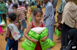 A newly arrived Rohingya girl carries food rations in Kutupalong, Bangladesh, Saturday, Sept. 30, 2017.