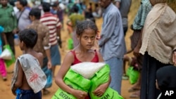 FILE - A newly arrived Rohingya girl carries food rations in Kutupalong, Bangladesh, Sept. 30, 2017. 