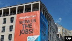 Cartel en protesta del tratado en el edificio de la Federación Americana de Trabajadores (AFL-CIO) en Washington, que dice "Muéstrenos los empleos".