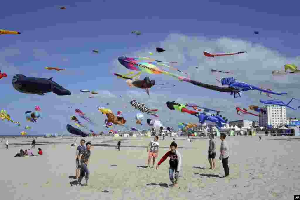 Boys play soccer as kites are seen in the sky during the 31st International Kite Festival in Berck, northern France.