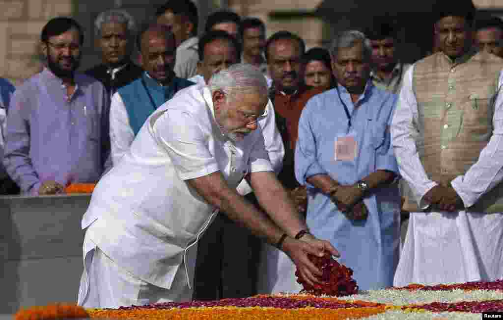Perdana Menteri India terpilih Narendra Modi menyebar kelopak bunga di tempat penghormatan untuk Mahatma Gandhi, New Delhi, sebelum dilantik Senin (26/5). (Reuters/Adnan Abidi)
