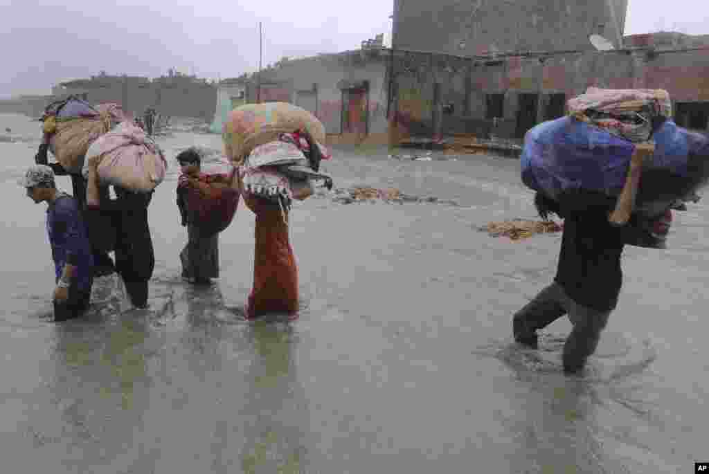 Local residents wade through a flooded area during a heavy monsoon rain in Yar Mohammad village near Karachi, Pakistan.