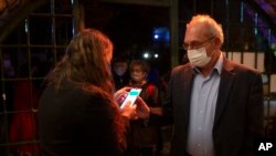 Seorang pria menunjukkan "paspor hijau", bukti bahwa dia sudah divaksinasi COVID-19, pada malam pembukaan pertunjukan di Teater Khan, Yerusalem, Selasa, Feb. 23, 2021. (AP Photo/Maya Alleruzzo).