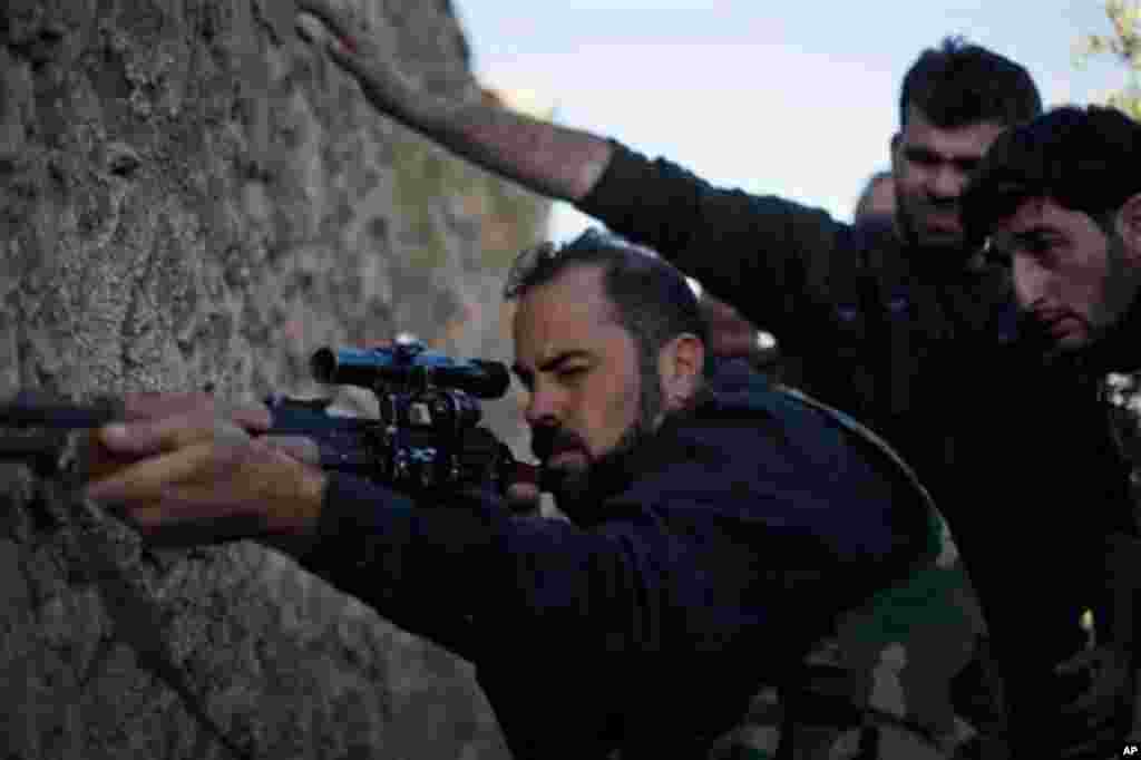 A Free Syrian Army sniper fires his rifle towards Syrian Army positions during an assault on a military base in Tal Sheen, Syria, Saturday, Dec 15, 2012