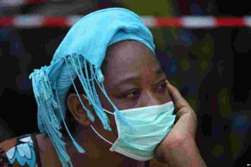 A woman who lost a relative after a four-story building collapsed watches the rescue workers search for bodies amongst the rubble in Lagos, Nigeria, Friday, July 8, 2011. Authorities say the building collapsed in a busy market in the commercial capital of