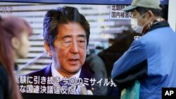 Passers-by look at a TV screen showing Japanese Prime Minister Shinzo Abe speak on North Korea's rocket launch, in Tokyo, Feb. 7, 2016.